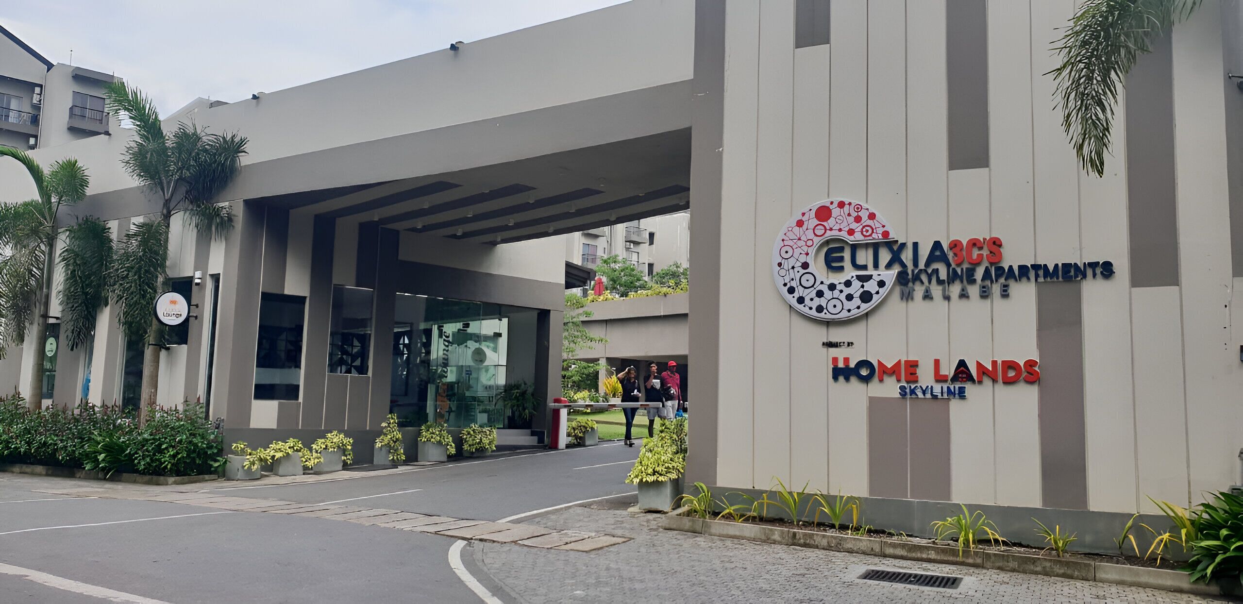 A modern building with a sign for 'Elicia's Skyline Apartments' and 'Home Lands Skyline'.