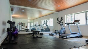 Une salle de sport équipée de tapis de course, de vélos elliptiques et de matériel de musculation.
