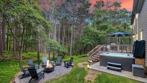 A backyard with a fire pit, outdoor seating, a hot tub, and a staircase leading to a deck. - Game Room, Hot Tub, Fire Pit, Dogs OK, Indoor Pool (Long Pond)