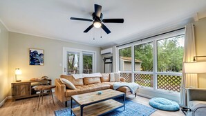 A spacious living room with a leather sofa, wooden coffee table, and a ceiling fan. - Game Room, Hot Tub, Fire Pit, Dogs OK, Indoor Pool (Long Pond)