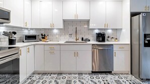 A modern kitchen with white cabinets, stainless steel appliances, and a patterned floor. - Game Room, Hot Tub, Fire Pit, Dogs OK, Indoor Pool (Long Pond)