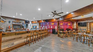 A spacious restaurant with a long bar, wooden chairs, and tables. - Game Room, Hot Tub, Fire Pit, Dogs OK, Indoor Pool (Long Pond)