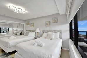 A hotel room with two beds, a large window, and artwork on the walls.