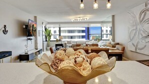 A modern dining area with a central table displaying an assortment of desserts in a decorative bowl.