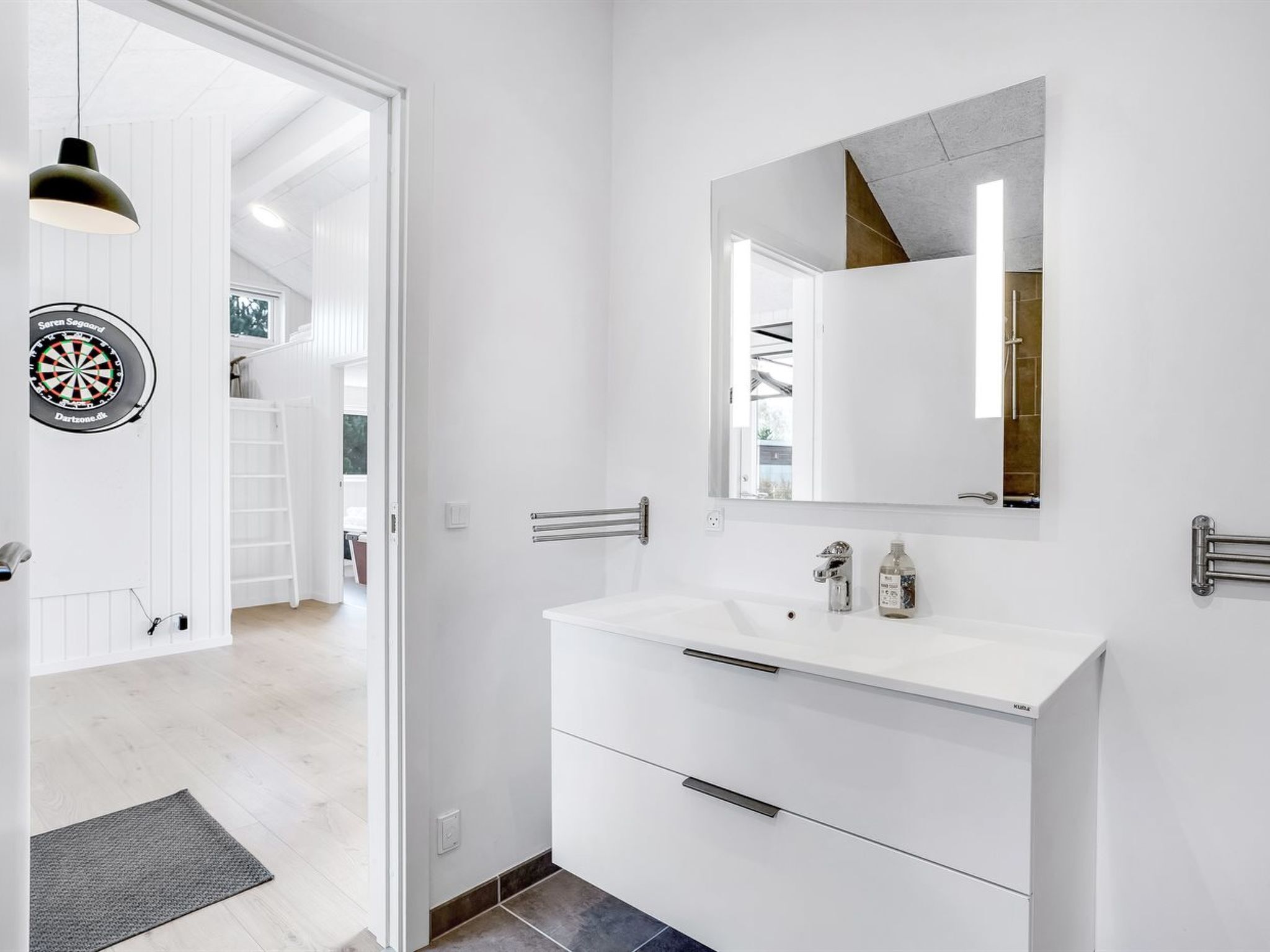 A modern bathroom with a white vanity, a mirror, and a towel rack.