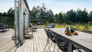 Eine Terrasse im Freien mit Holztisch, Stühlen und Grill.