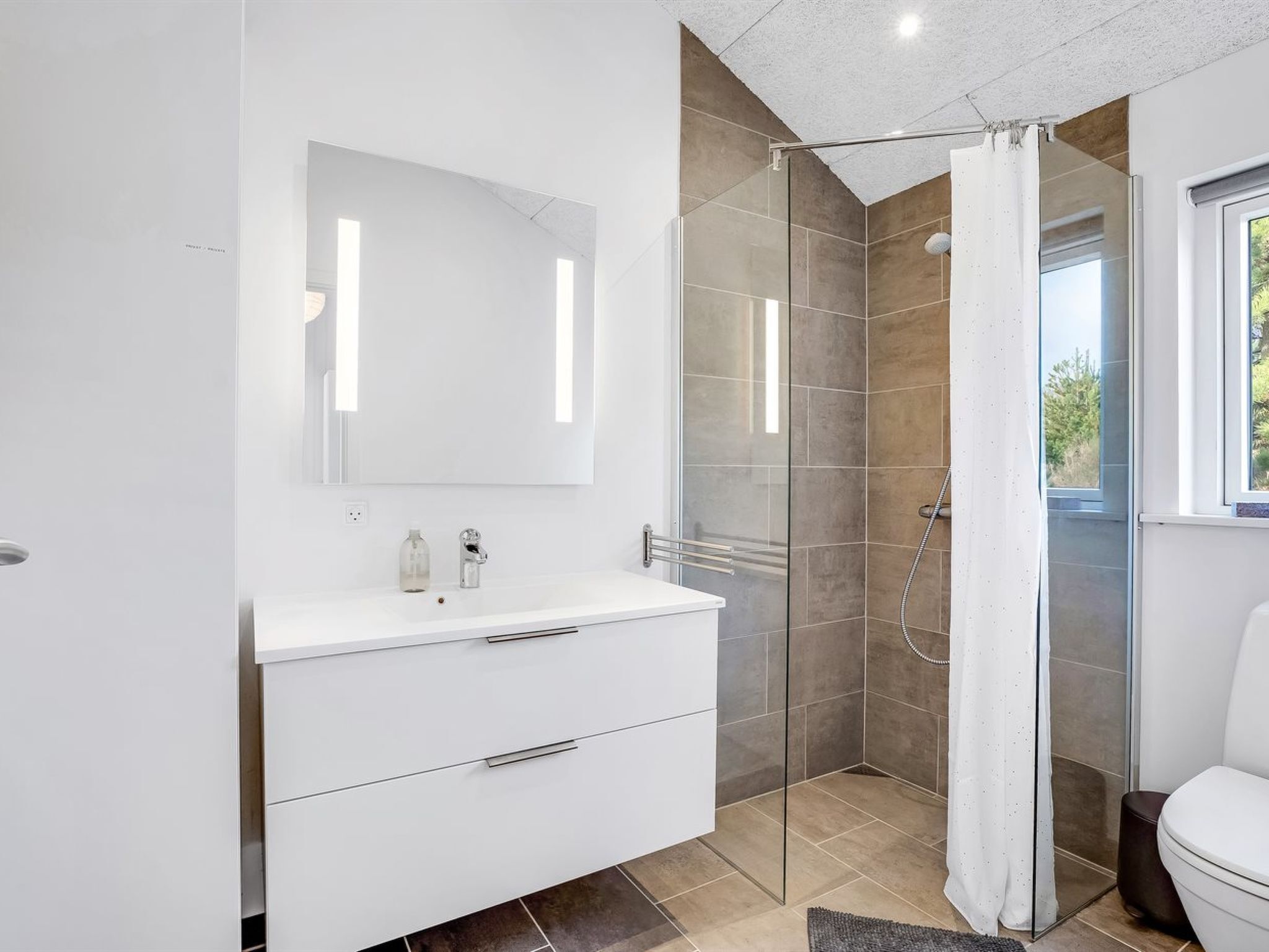 A modern bathroom with a glass shower enclosure, a white vanity with a mirror, and a toilet.