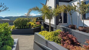 Een modern gebouw met een balkon, omringd door verschillende planten en struiken.