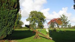 A seesaw in a grassy area with trees and a clear sky. - Gîte 10 minutes from the beach (Hudimesnil)
