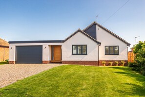 A modern two-story house with a garage, a well-maintained lawn, and a brick foundation.