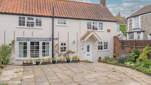 A two-story house with a tiled roof, a front door, and a small garden with potted plants. - Rose Cottage | Dog-Friendly Village Stay, 2 Minutes from the Beach (Winterton-on-Sea)