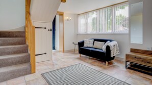 A staircase with wooden handrails, a dark blue sofa with patterned cushions, a patterned rug, and a window with vertical blinds.