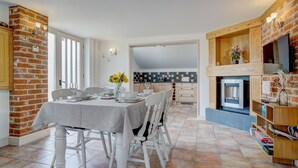 A dining area with a brick wall, a fireplace, and a TV mounted on the wall.