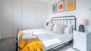 A neatly arranged bedroom with a bed, bedside tables, and a wardrobe. - Sanderlings | Dog Friendly Family House, 5 Mins to Winterton Beach (Winterton-on-Sea)