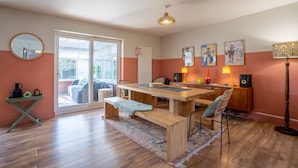 A dining area with a wooden table, benches, and chairs. There is a large window with a view of the outdoors. - Sanderlings | Dog Friendly Family House, 5 Mins to Winterton Beach (Winterton-on-Sea)