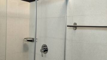 Um chuveiro moderno com porta de vidro, chuveiro manual e painel de controle.