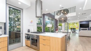 Cocina moderna con una isla central, electrodomésticos de acero inoxidable y un amplio ventanal con vistas a zonas verdes.