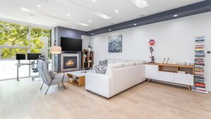 Una sala de estar moderna con chimenea, sofá blanco y estantería.