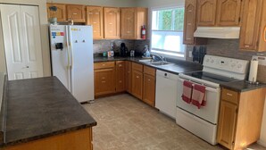 A kitchen with wooden cabinets, a white refrigerator, a stove, and a dishwasher.