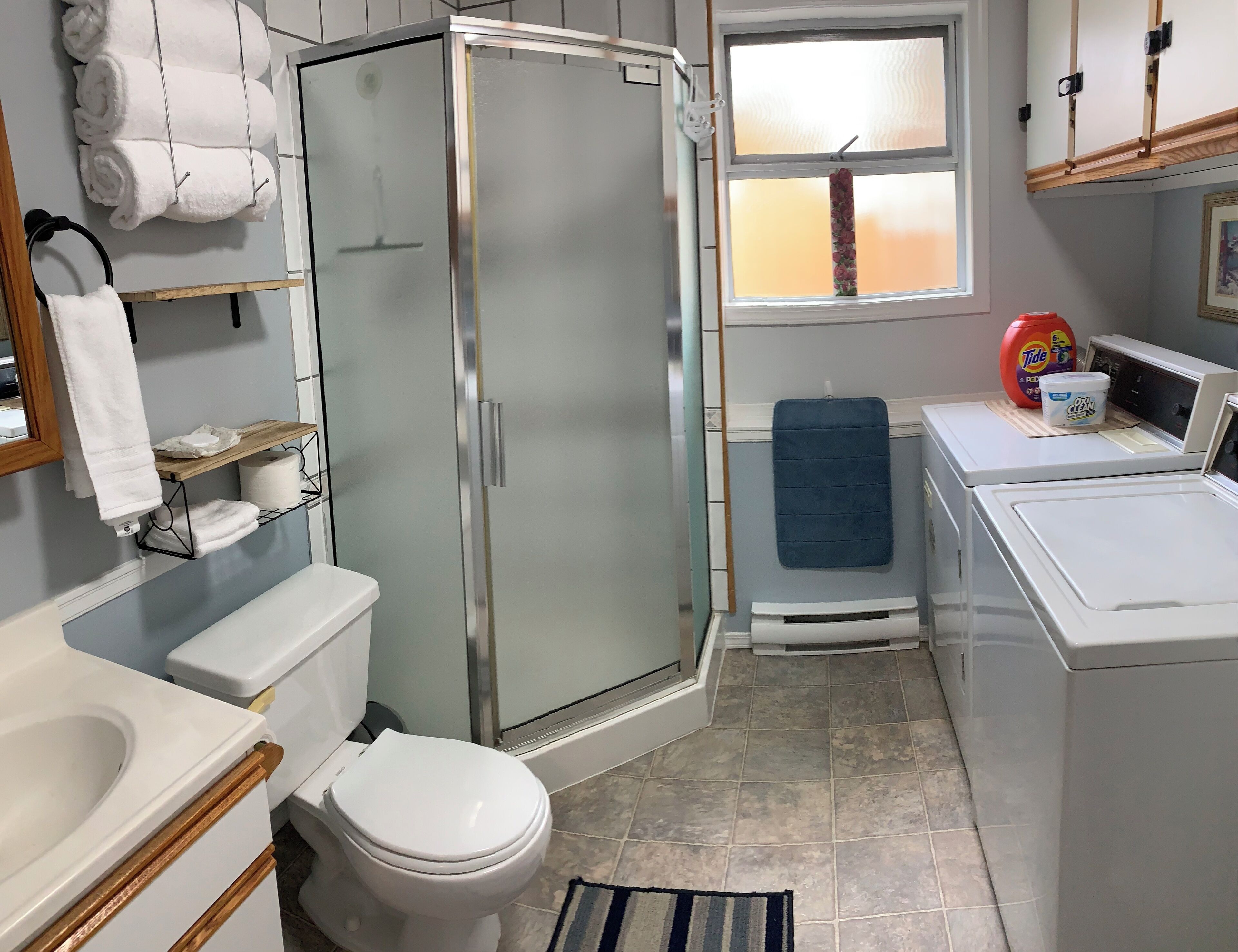 A bathroom with a toilet, a shower, a sink, and a washing machine.
