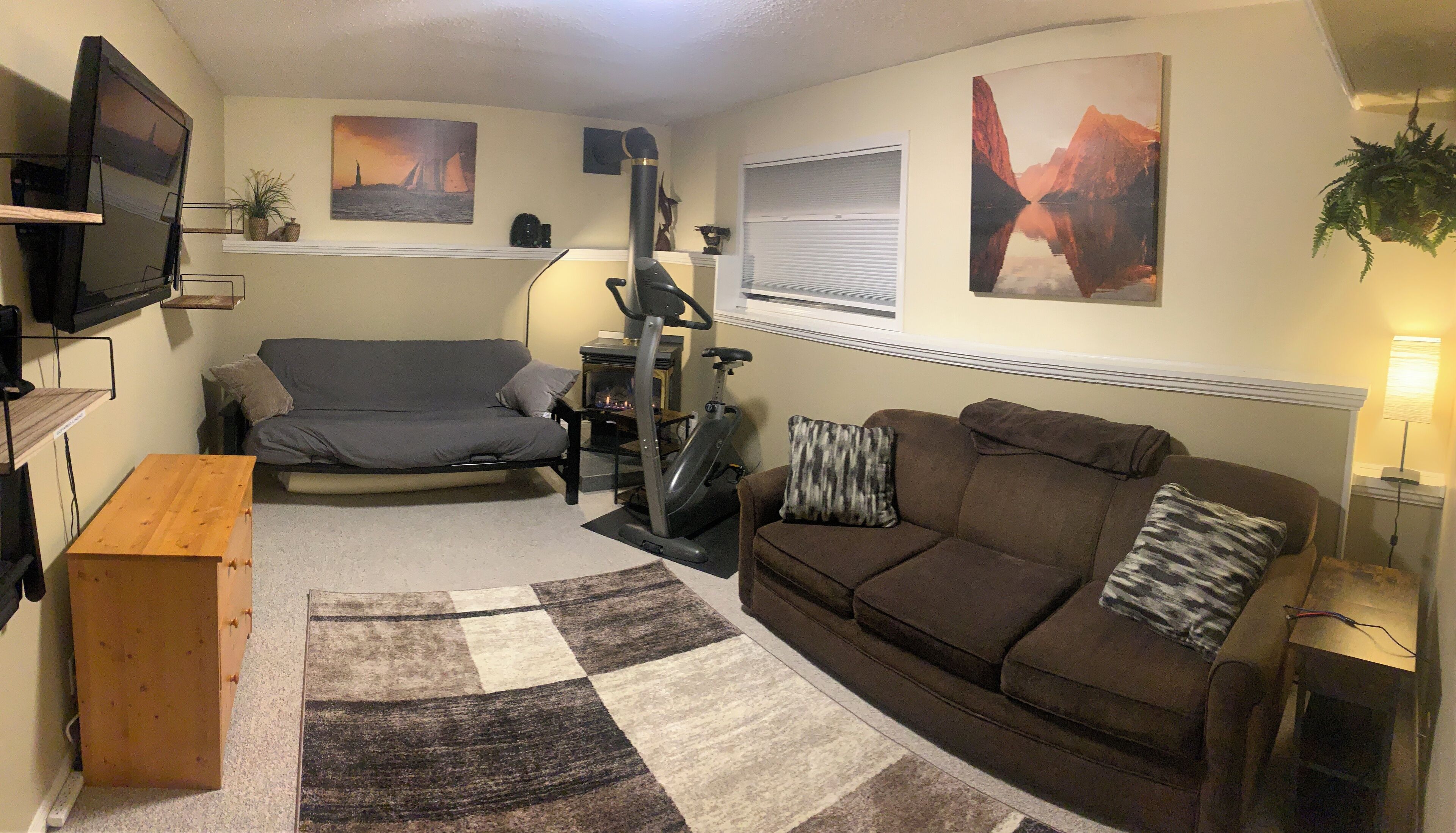 A compact living room with a sofa, a couch, a TV, a fireplace, and artwork on the walls.