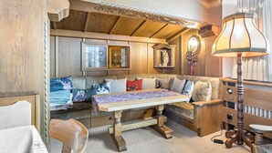 Una habitación acogedora con un banco de madera, una mesa, una lámpara y un sofá con cojines.