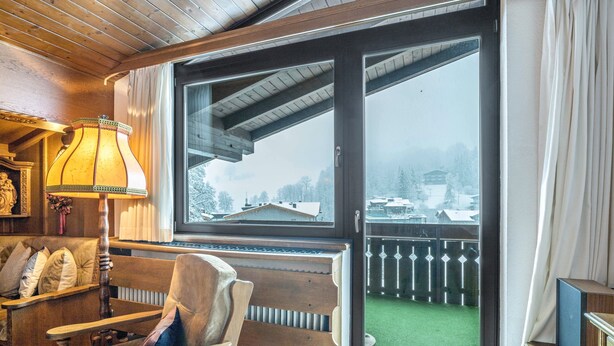 Habitación acogedora con un banco de madera, una lámpara y un ventanal con vistas a un paisaje nevado.