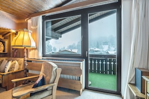 Ein gemütliches Zimmer mit einer hölzernen Bank, einer Lampe und einem großen Fenster mit Blick auf eine verschneite Landschaft.