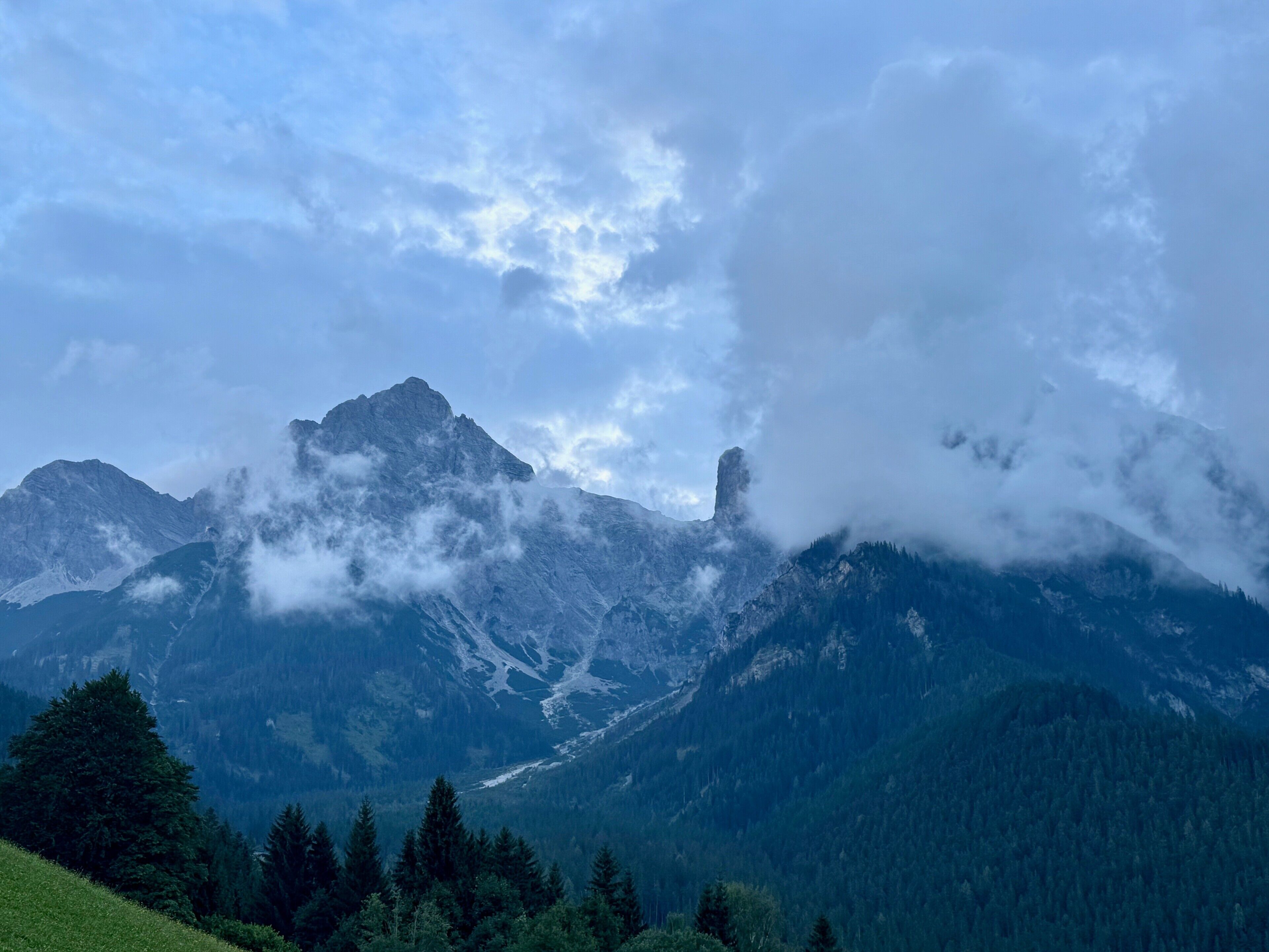 Een berglandschap met een opvallende bergtop, beboste valleien en een heldere lucht.