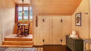 A wooden interior with a dining table and chairs, a dresser, and a window with a view. - Guest Rooms "König-Max-ll" and "Ludwig-Thoma" (Oberammergau)