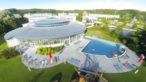 A modern building with a circular roof, a swimming pool, and a surrounding lawn. - Holiday Apartment 'Inselliebe Rügen' with Balcony, Ahoi Pool & Sauna Included (Sellin)