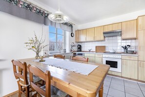 Ett kök med träskåp, en vit spis och ett matbord med stolar.