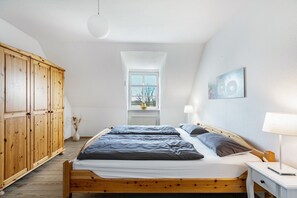 Una camera da letto con un letto in legno, un comodino, una lampada, una finestra e un armadio in legno.