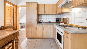 Eine Küche mit Holzschränken, einer Arbeitsplatte, einem Herd und einem Spülbecken.