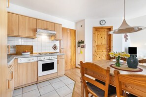 Une cuisine avec des meubles de rangement en bois, une cuisinière et une table à manger avec des chaises.