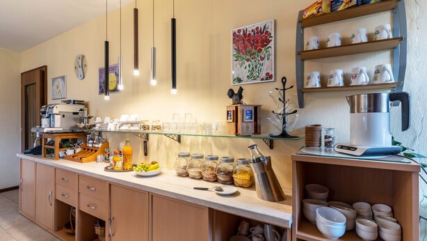 Una cocina con una cafetera, un frutero y distintos utensilios de cocina.