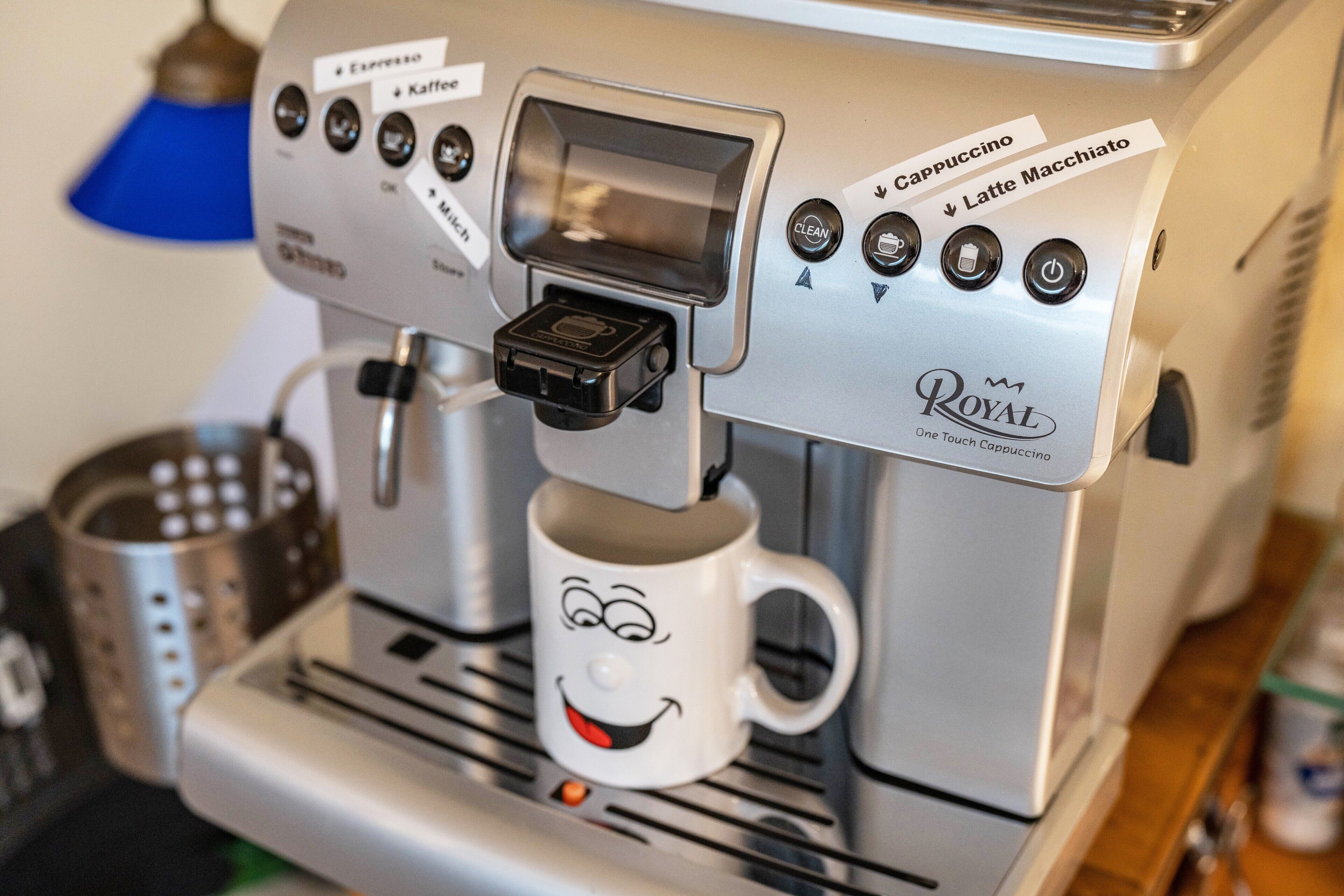 A coffee machine with a cup of coffee and a mug with a smiling face.