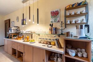 Une cuisine équipée d’une machine à café, d’un panier de fruits et de divers ustensiles de cuisine.