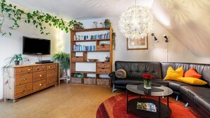 Una sala de estar con televisor, estanterías, sofá y una mesa de centro.