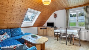 A cozy room with a wooden ceiling, a sofa, a dining table with chairs, a TV, and a window with curtains. - Apartment 'Ferienwohnung Waldblick' with Mountain View, Shared Terrace and Wi-Fi (Elzach)