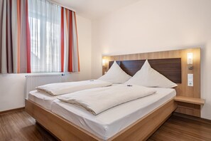 Un lit double avec une tête de lit en bois, des tables de chevet et une fenêtre avec des rideaux.