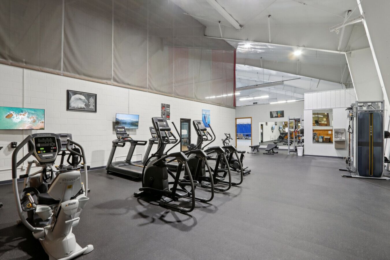 A gym with treadmills, elliptical machines, and weight equipment.