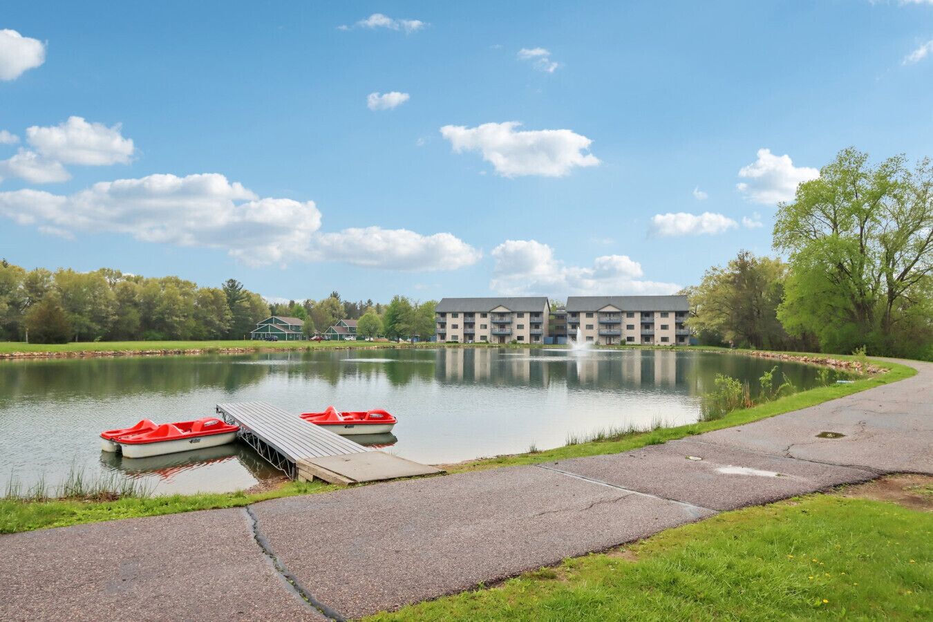 A lakeside view with a dock, boats, and a building with multiple balconies.