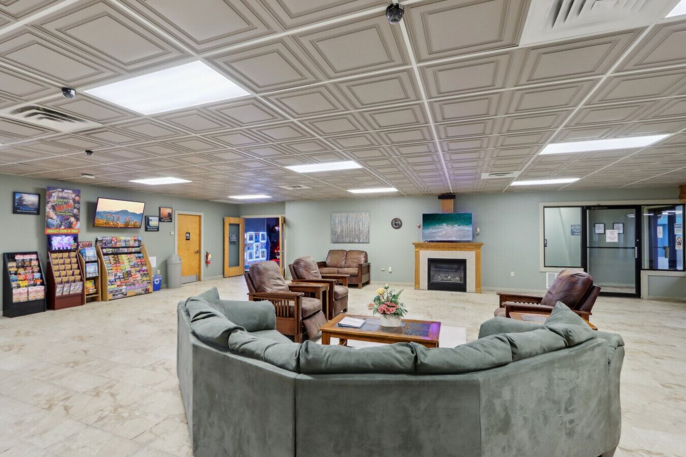 Un hall d’entrée spacieux avec un plafond haut, une cheminée, des sièges confortables et un présentoir rempli de magazines et de livres.