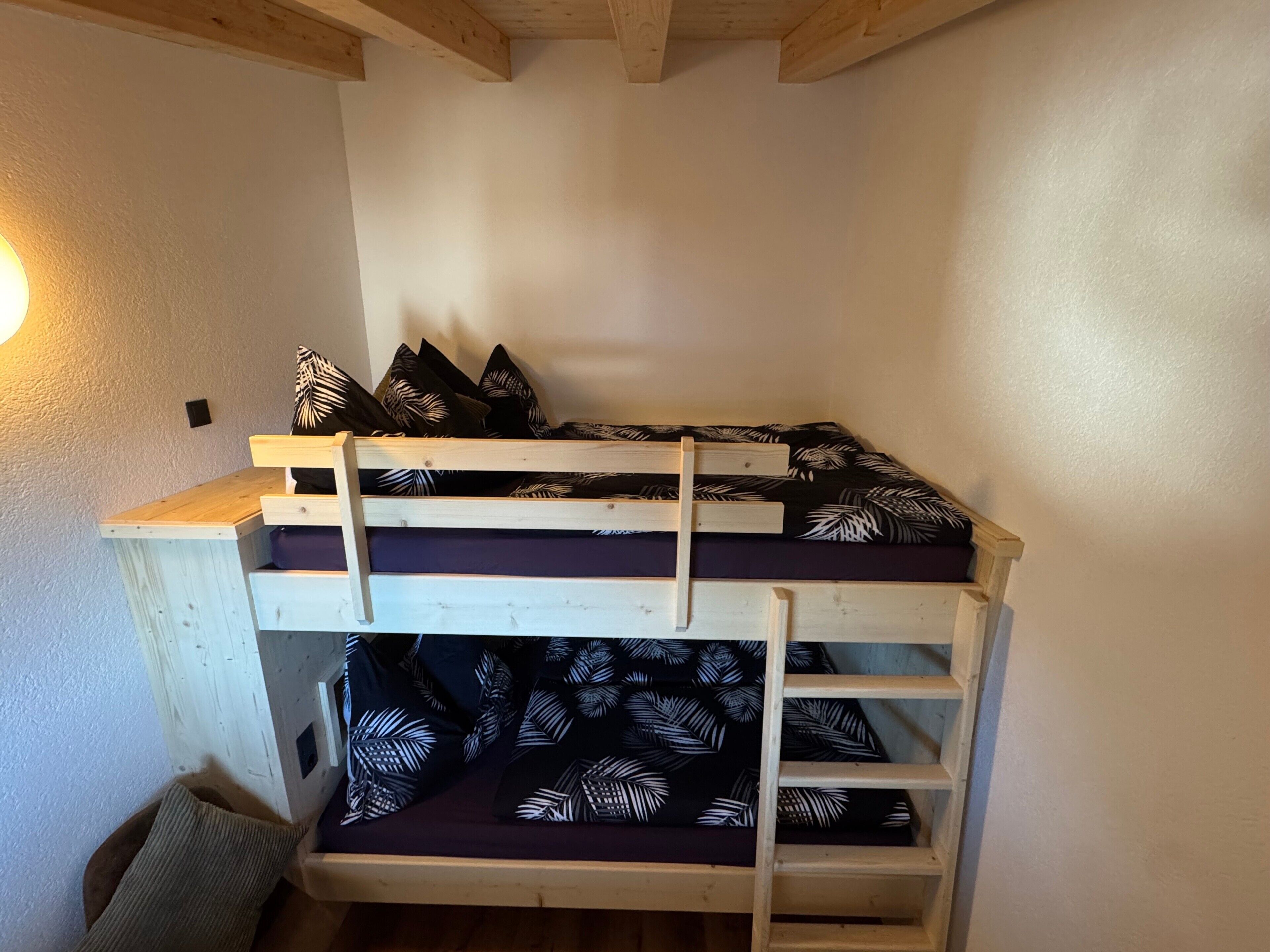 Una cama litera con estructura de madera y un colchón estampado con motivos de hojas.