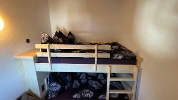 Una cama litera con estructura de madera y un colchón estampado con motivos de hojas.
