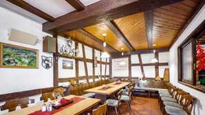 A restaurant with wooden tables and chairs, a high ceiling with exposed beams, and a view of the countryside through the windows. - Room 'Zimmer 8' with Shared Terrace, Shared Garden and Wi-Fi (Ebenweiler)