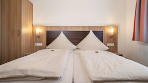 A double bed with two pillows, wooden headboard, bedside lamps, and a wardrobe. - Room 'Zimmer 8' with Shared Terrace, Shared Garden and Wi-Fi (Ebenweiler)