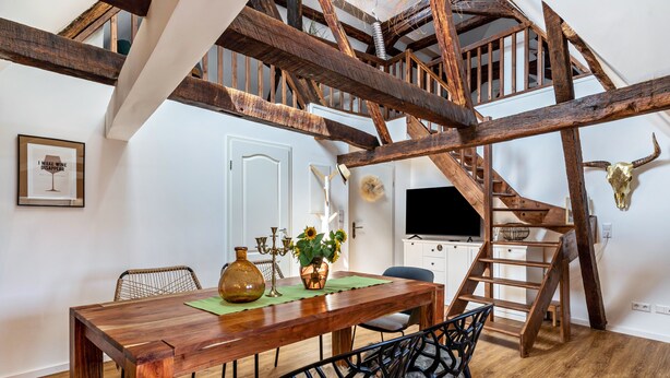 A dining area with a wooden table, chairs, and a staircase with a bull skull decoration.