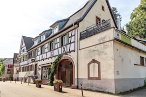 Ein traditionelles Fachwerkhäuschen mit großem Bogenportal, einem Balkon und Blumentöpfen.
